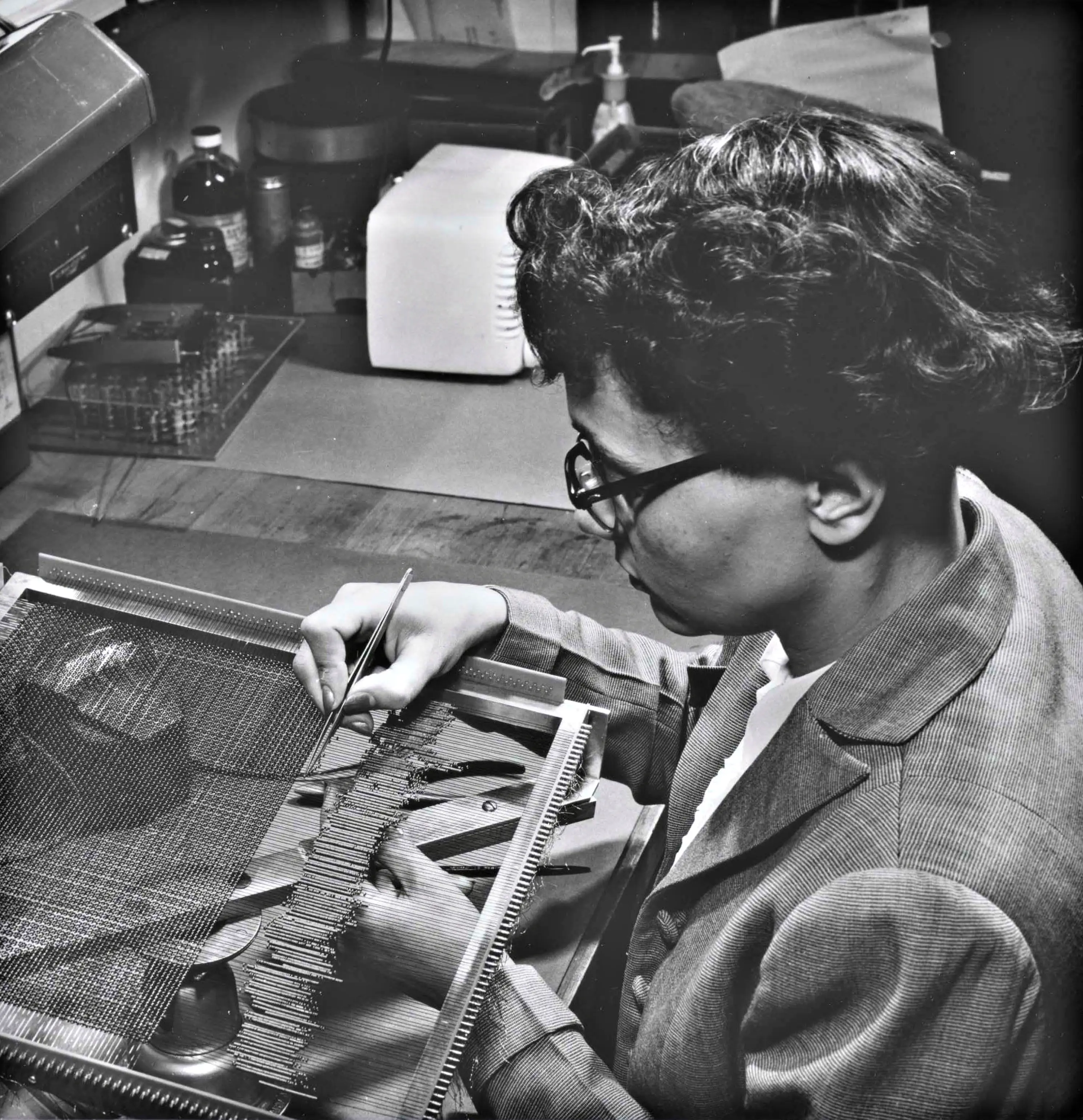 Historical photo of a worker weaving rope memory for the Apollo Guidance Computer used in NASA's Apollo program.